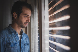 Sad looking man gazing out window needs to know how to detox from meth